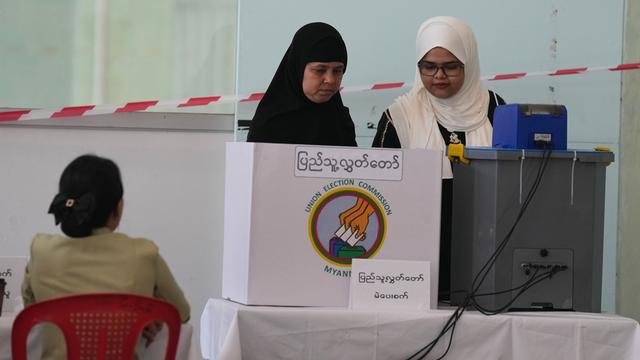Blick auf zwei Frauen mit Koptuch. Eine steht vor einem Sichtschutz zur Stimmabgabe, die andere vor der Wahlurne aus Plastik.