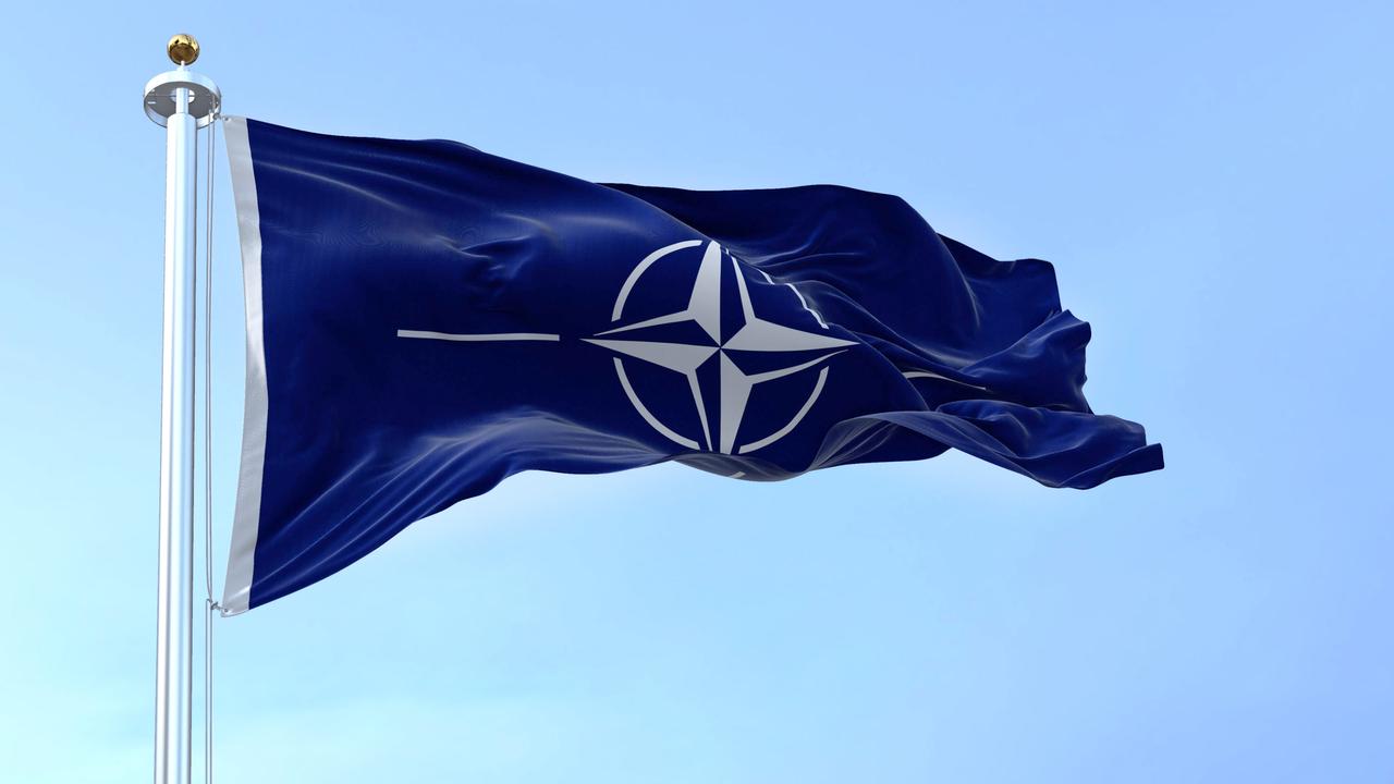Die Flagge der NATO (North Atlantic Treaty Organization) weht an einem klaren Tag im Wind.
