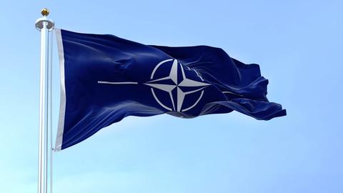 Die Flagge der NATO (North Atlantic Treaty Organization) weht an einem klaren Tag im Wind.