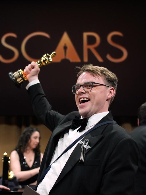 Regisseur Pawel Talankin hält den Oscar mit gestrecktem Arm in die Luft und freut sich über die Auszeichnung für seinen Dokumentarfilm "Ein Nobody gegen Putin".