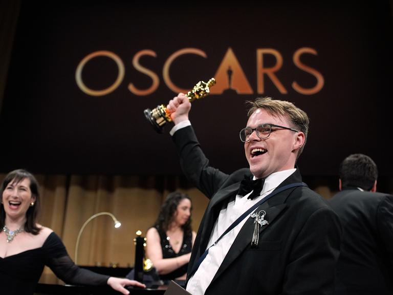 Regisseur Pawel Talankin hält den Oscar mit gestrecktem Arm in die Luft und freut sich über die Auszeichnung für seinen Dokumentarfilm "Ein Nobody gegen Putin".