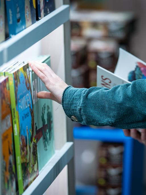 Bücherregal mit einer Hand, die ein Buch aus dem Regal nimmt.