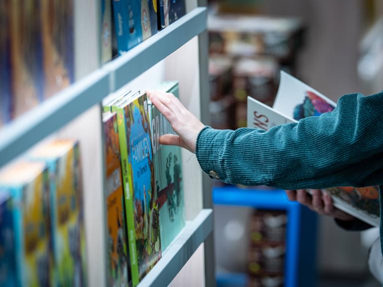 Bücherregal mit einer Hand, die ein Buch aus dem Regal nimmt.