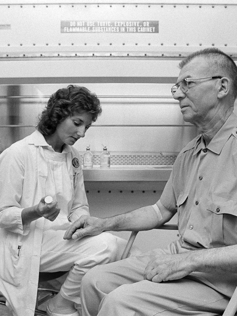 Ein Schwarz-Weiß Foto zeigt eine Onkologiekrankenschwester, die einen männlichen Patienten auf eine Chemotherapie vorbereitet. 