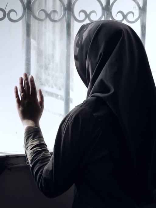 Sehnsuchtsort Kino: Das iranische Kino hat eine lange Tradition. Hier ein Foto aus dem Dokumentarfilm Stairless Dreams. Eine verschleierte Frau schaut versonnen aus einem vergitterten Fenster, ihre Hand berührt die Scheibe. 