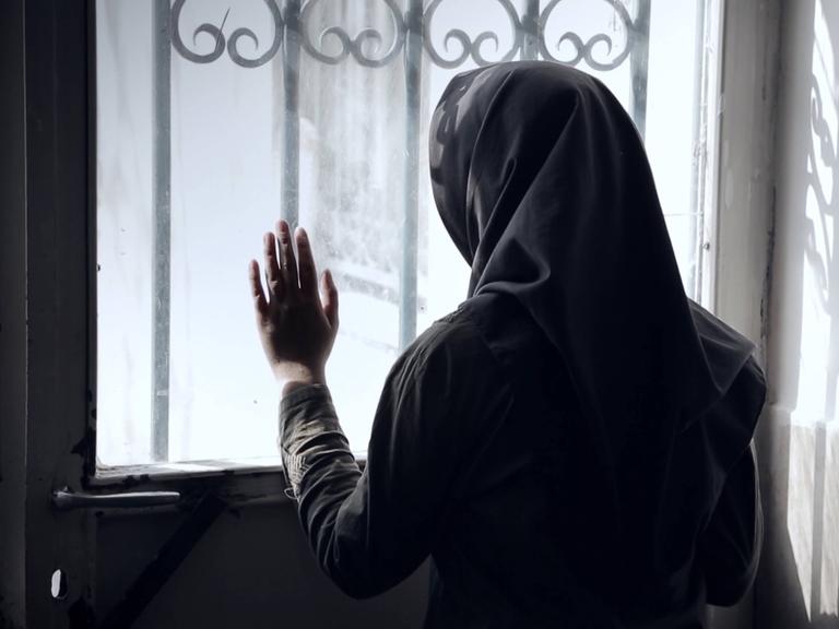 Sehnsuchtsort Kino: Das iranische Kino hat eine lange Tradition. Hier ein Foto aus dem Dokumentarfilm Stairless Dreams. Eine verschleierte Frau schaut versonnen aus einem vergitterten Fenster, ihre Hand berührt die Scheibe. 