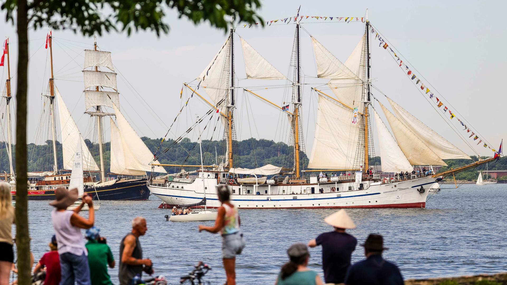 Zuschauer schauen sich die Windjammer-Parade der Kieler Woche an.