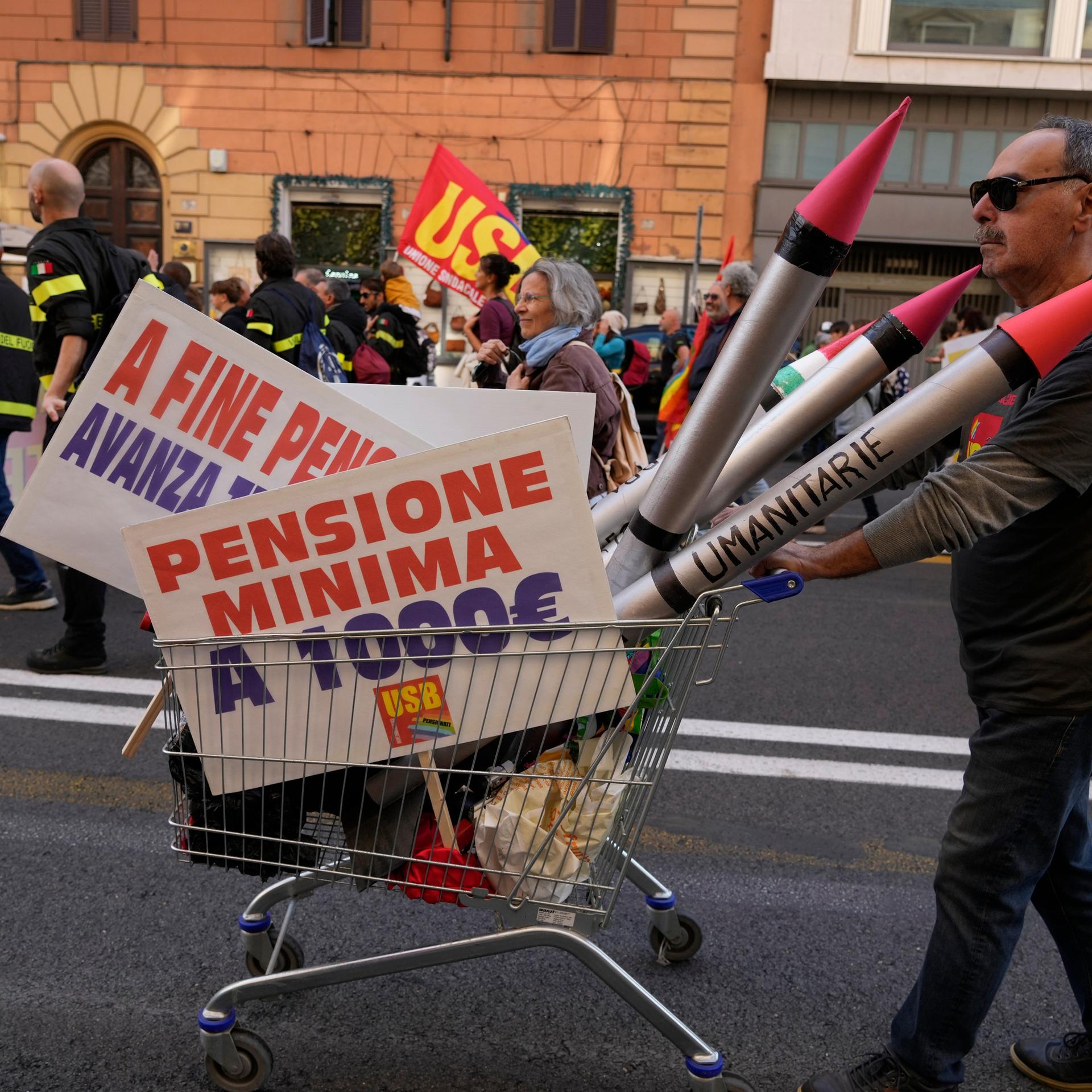 Rom: Ein Demonstrant schiebt während eines landesweiten Generalstreiks einen Einkaufswagen, auf dem Attrappen von Raketen und Plakate mit der Forderung nach einer Mindestrente von 1.000 Euro zu sehen sind.