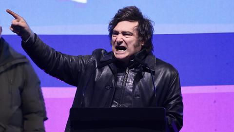 Der argentinische Präsident Javier Milei steht auf einer Bühne und reckt die rechte Hand mit ausgestrecktem Zeigefinger ins Publikum. 