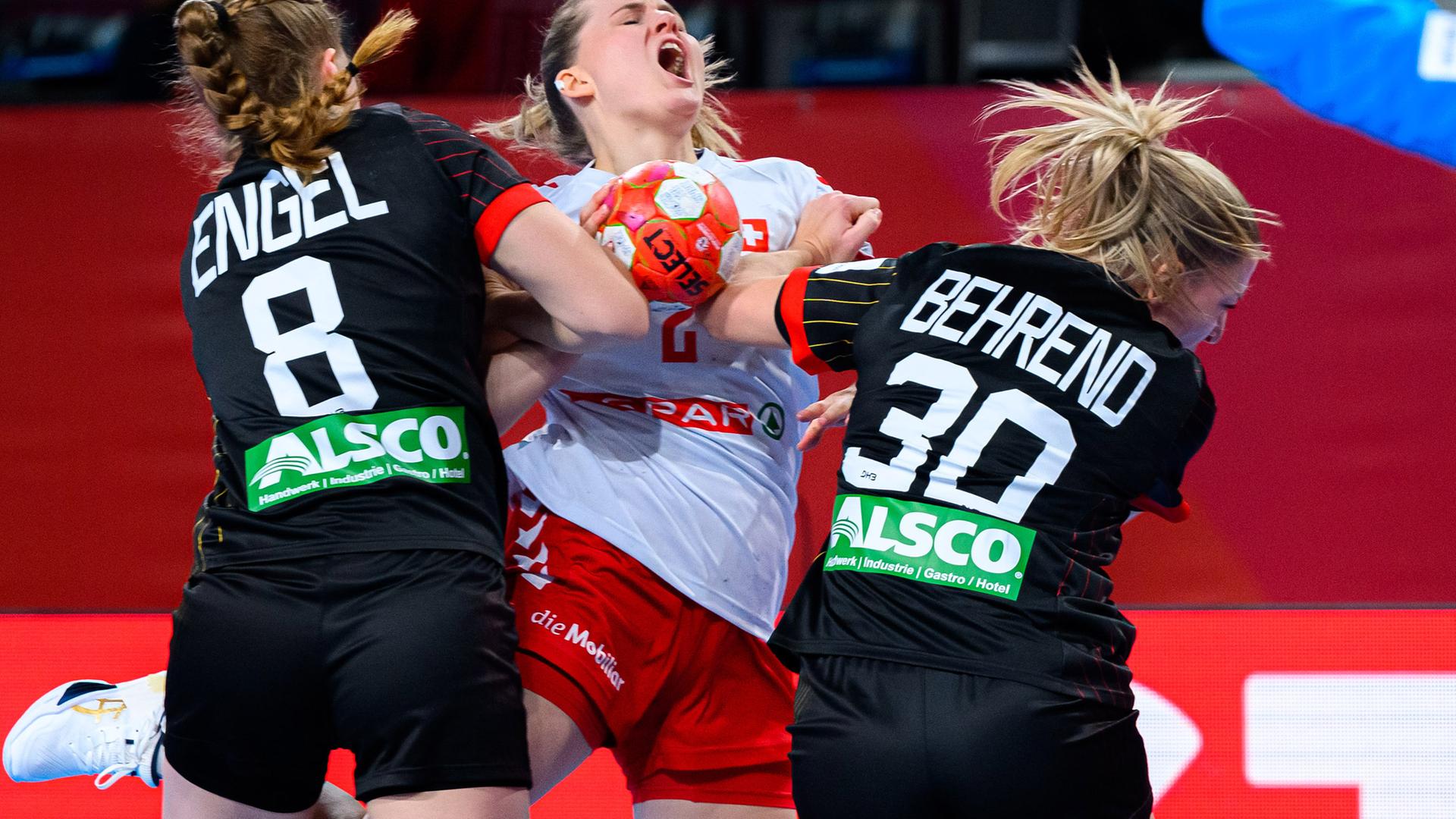 Zwei Handball-Spielerinnen blocken einen Angriff einer Spielerin des gegnerischen Teams ab. 