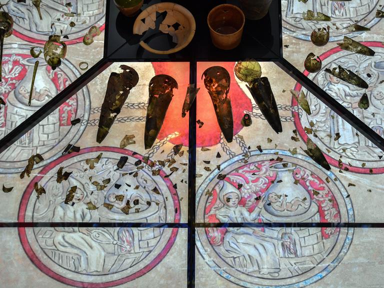 Auf einem gläsernen Tisch sind Hinterlassenschaften aus einer Wittenberger Alchemistenwerkstatt ausgestellt.