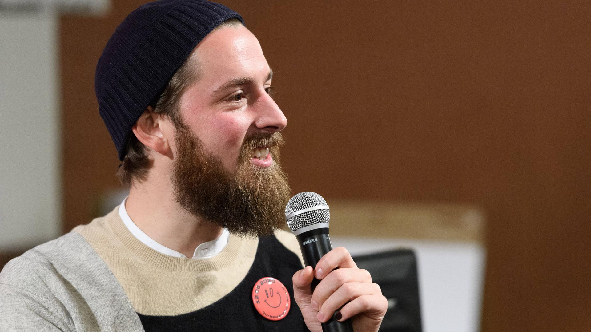 Philip Siefer spricht auf einem Podium bei einer Veranstaltung in Berlin in ein Mikrofon.