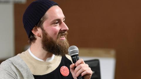 Philip Siefer spricht auf einem Podium bei einer Veranstaltung in Berlin in ein Mikrofon.