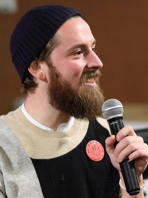 Philip Siefer spricht auf einem Podium bei einer Veranstaltung in Berlin in ein Mikrofon.