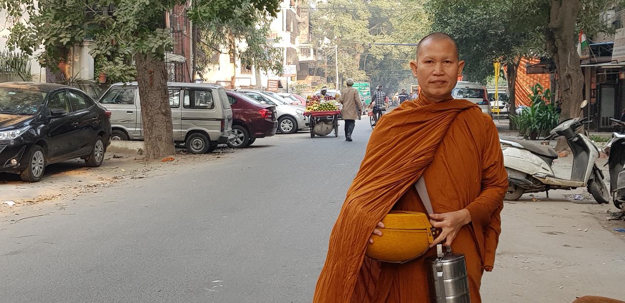 Der buddhistische Mönch Mr. Chandi in senfgelber Robe auf dem Bhogal Market in Delhi