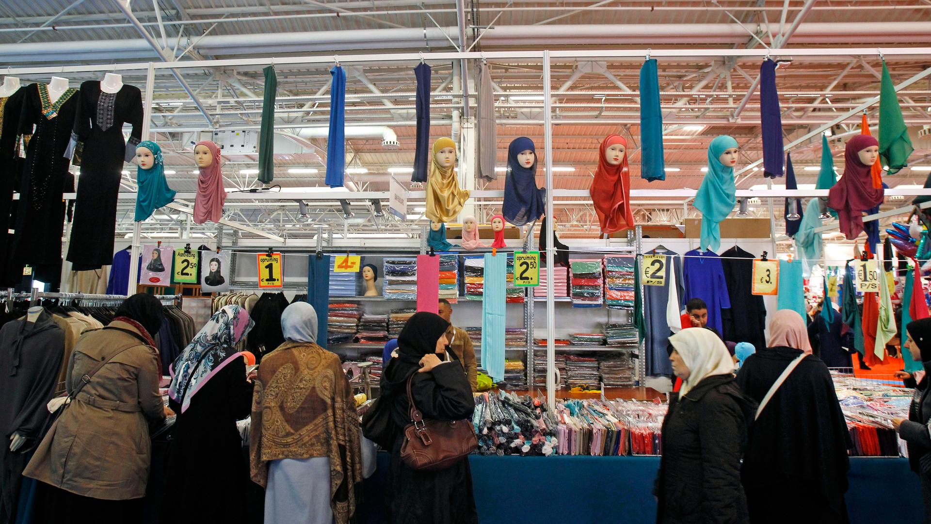 Frauen mit Kopftüchern stehen vor einem Verkaufsstand.