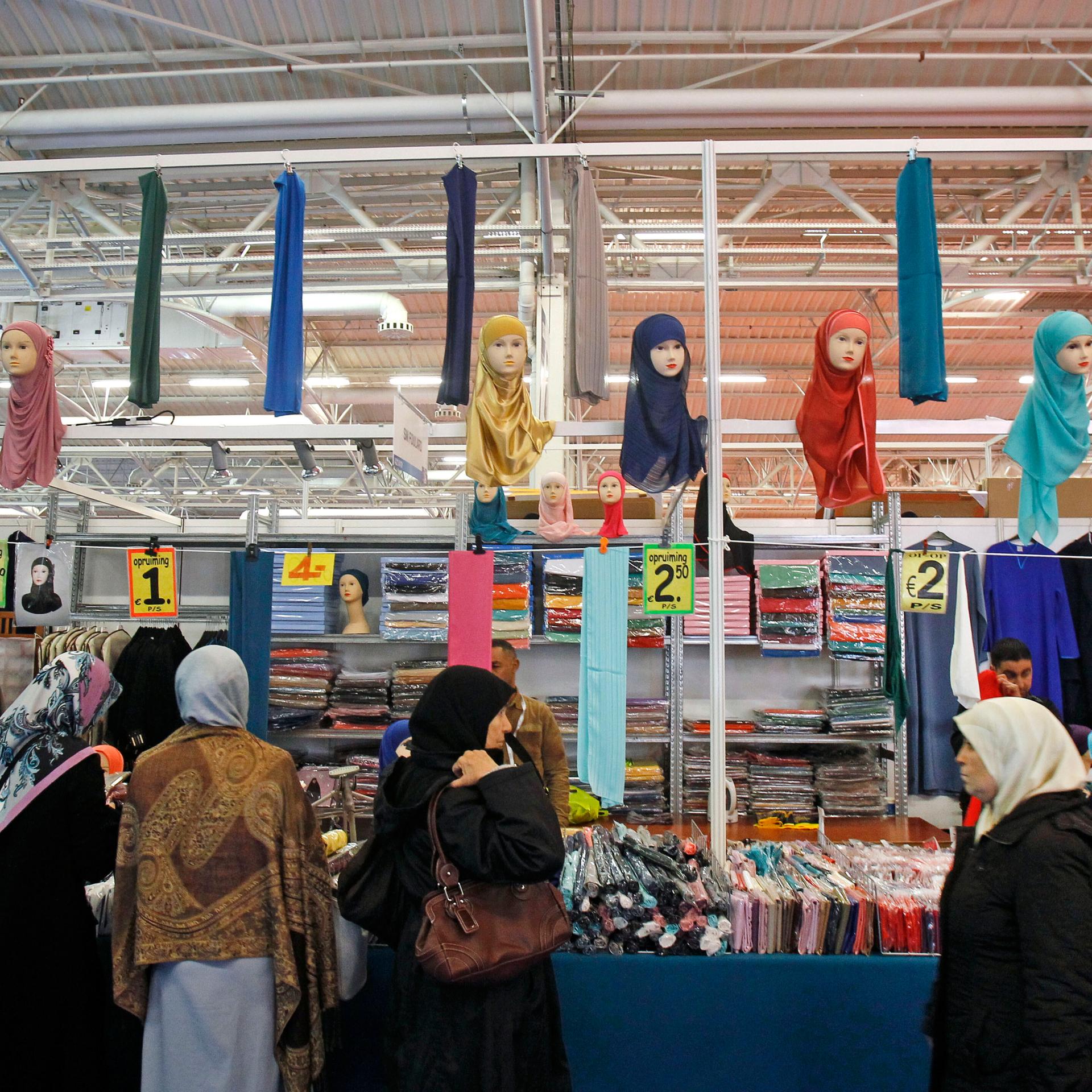 Frauen mit Kopftüchern stehen vor einem Verkaufsstand.