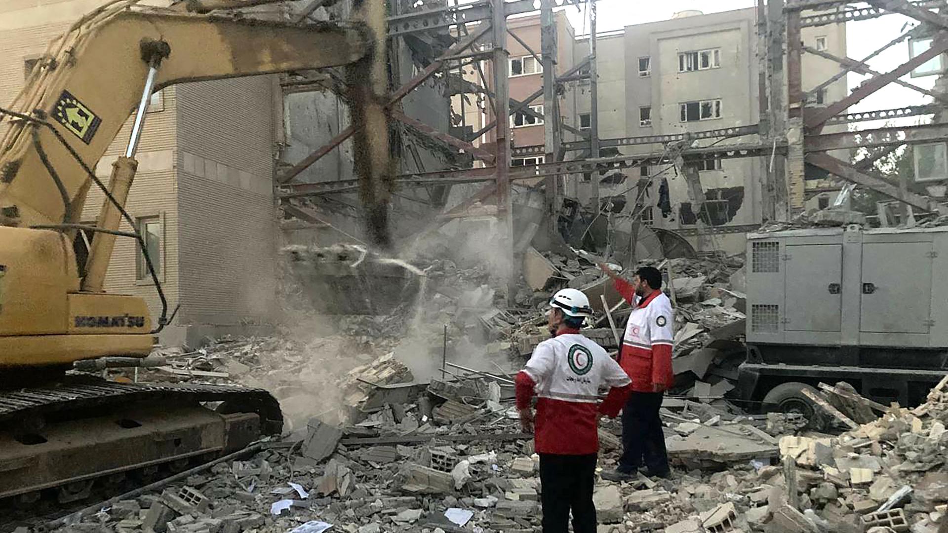 Das Bild zeigt eine Straßenszene in Teheran nach einem israelischen Luftangriff. Inmitten von Schutt arbeitet ein Bagger sowie zwei Arbeiter. Das Bild zeigt eine Straßenszene in Teheran nach einem israelischen Luftangriff. Inmitten von Schutt arbeitet ein Bagger sowie zwei Arbeiter.