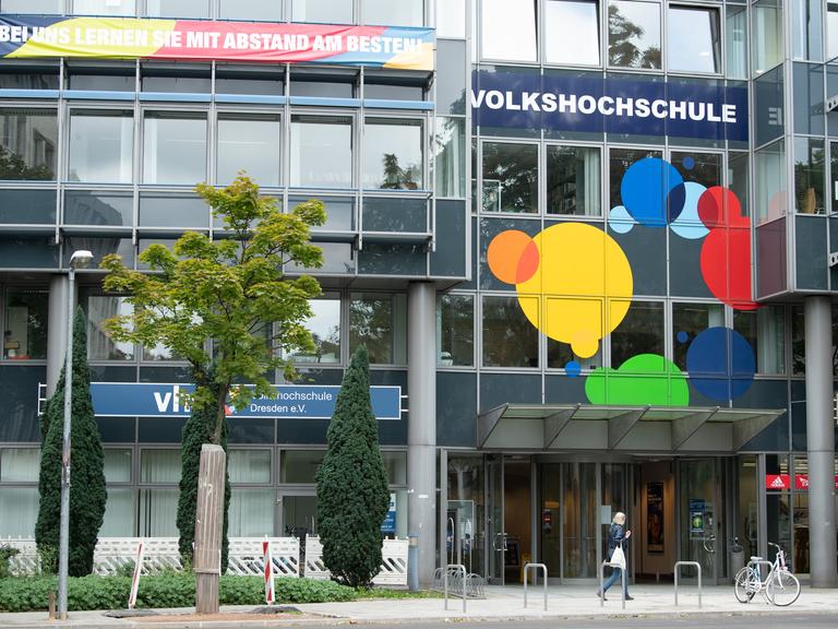 Eine Passantin geht vor dem Gebäude der Volkshochschule Dresden (VHS) entlang