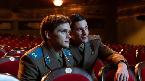 Zwei junge Soldaten in Uniformen der Roten Armee sitzen allein in einem Kinosaal.