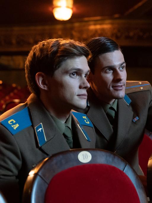 Zwei junge Soldaten in Uniformen der Roten Armee sitzen allein in einem Kinosaal.