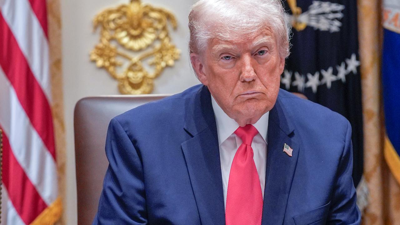 Ein Mann mit weißem Haar sitzt an einem Schreibtisch, dahinter zahlreiche Flaggen: US-Präsident Donald Trump im "Cabinet Room" des Weißen Hauses. Ein Mann mit weißem Haar sitzt an einem Schreibtisch, dahinter zahlreiche Flaggen: US-Präsident Donald Trump im "Cabinet Room" des Weißen Hauses.