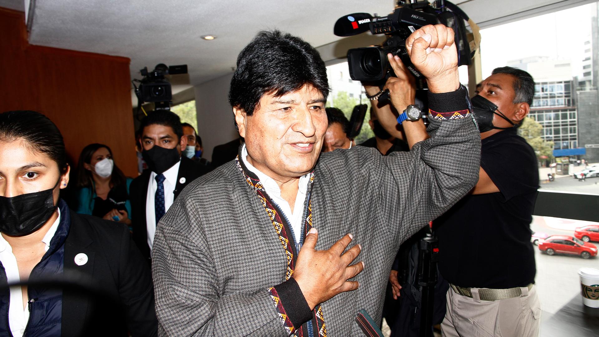 Morales steht mit erhobener Faust in einem Raum, neben ihm ein Mann mit einer Kamera und weitere Personen.