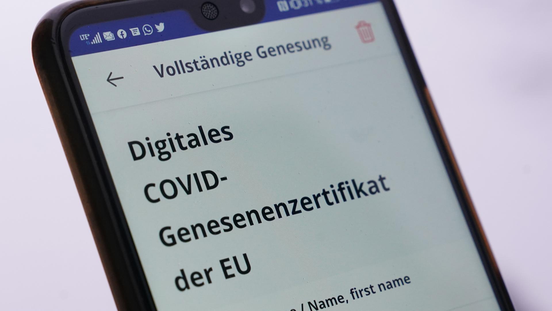 Ein Mann hält sein Smartphone mit einem digitalen Covid-Genesenenzertifikat Ein Mann hält sein Smartphone mit einem digitalen Covid-Genesenenzertifikat