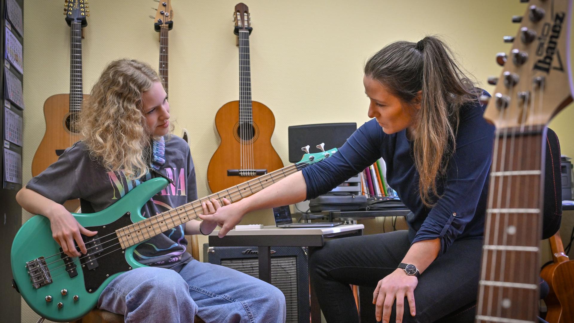 Die Schülerin Juno Bennewitz (l) übt E-Bass an der Städtischen Musikschule «Johann Crüger» und wird dabei von ihrer Lehrerin Ramona Geißler unterstützt. 