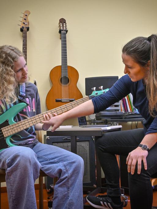 Die Schülerin Juno Bennewitz (l) übt E-Bass an der Städtischen Musikschule «Johann Crüger» und wird dabei von ihrer Lehrerin Ramona Geißler unterstützt. 