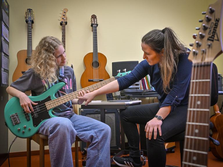 Die Schülerin Juno Bennewitz (l) übt E-Bass an der Städtischen Musikschule «Johann Crüger» und wird dabei von ihrer Lehrerin Ramona Geißler unterstützt. 