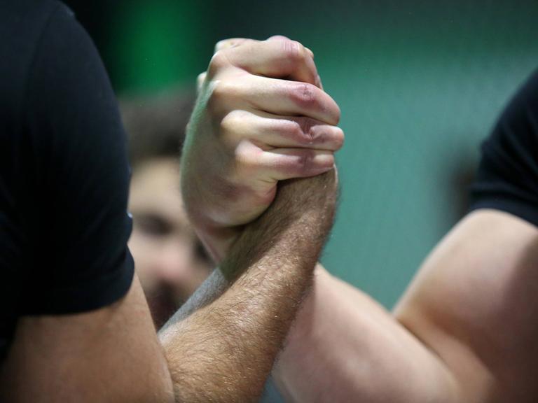 Zwei Armdrücker haben ihre Hände ineinander verschränkt für das Kräftemessen. 