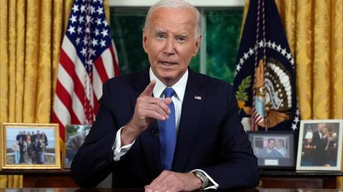 Joe Biden sitzt im schwarzen Anzug an seinem Schreibtisch im Oval Office und hebt den Finger seiner rechten Hand. (AP Photo/Evan Vucci, Pool)