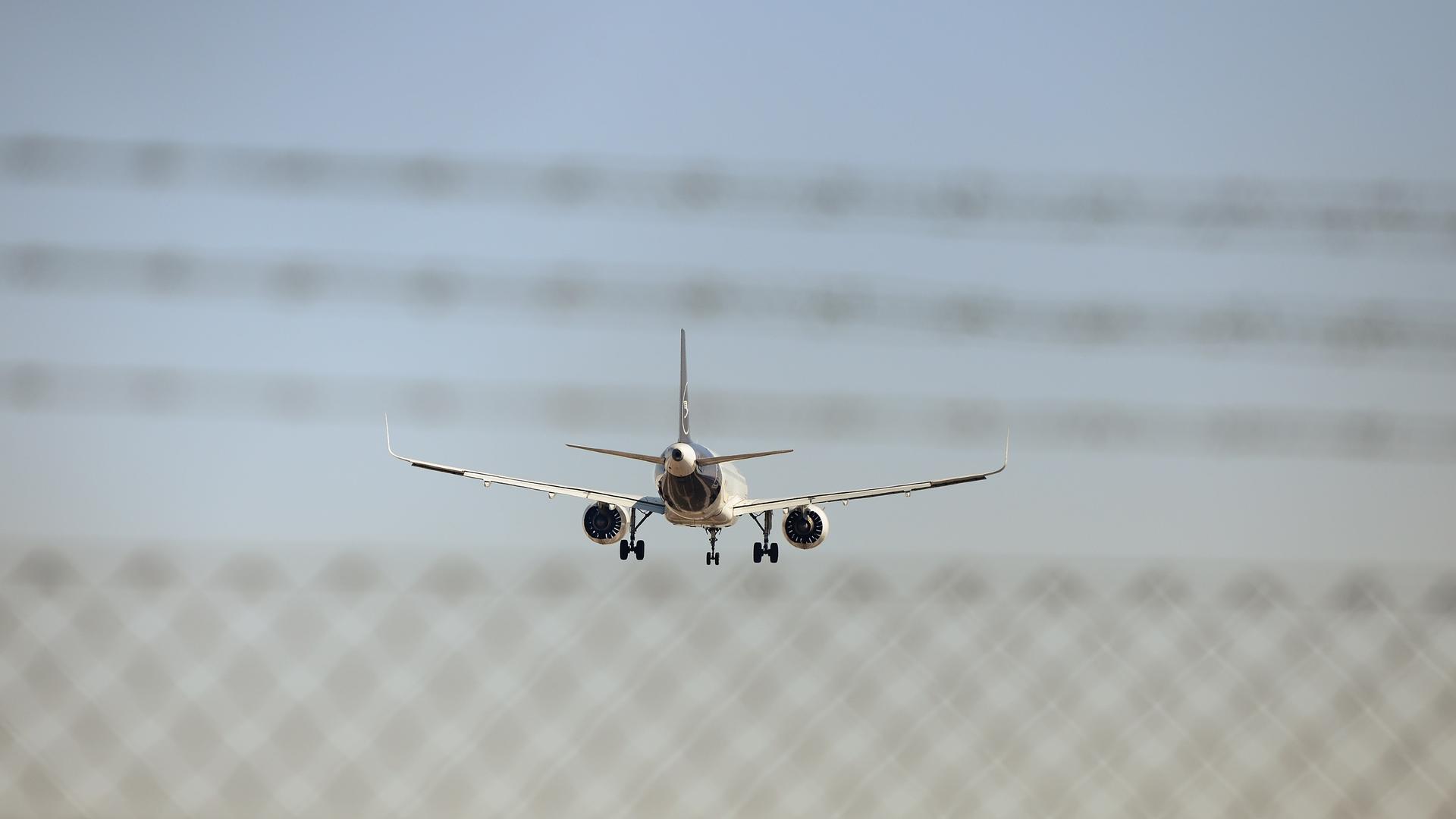 Symbolbild "Abschiebeflug" Landende Lufthansa Maschine hinter einem Zaun und Stacheldraht.