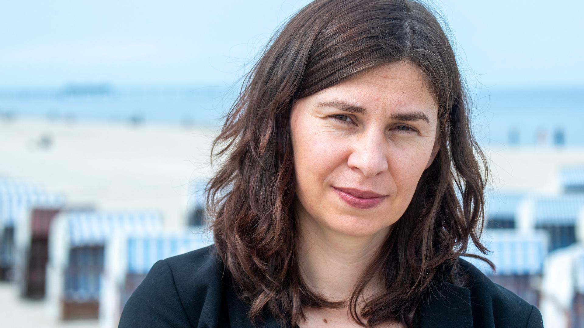 Tanja Maljartschuk steht an einem Strand auf der Ostsee-Insel Usedom und blickt ernst in die Kamera.