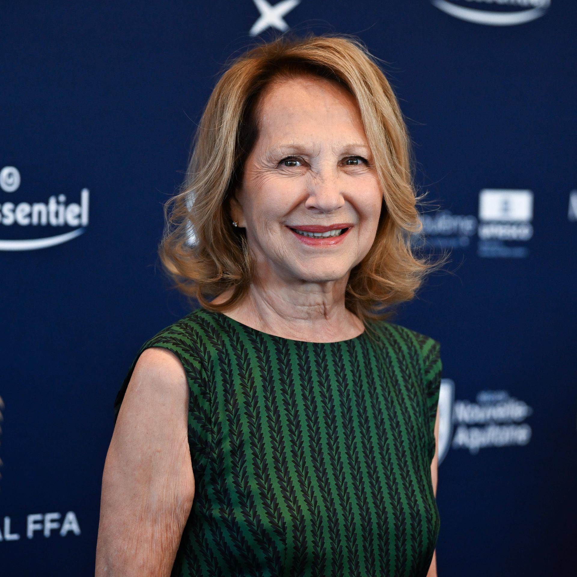 Nathalie Baye bei einem Filmfestival in Angouleme 2024; sie trägt ein grün-gestreiftes ärmelloses Top und lächelt in die Kamera.