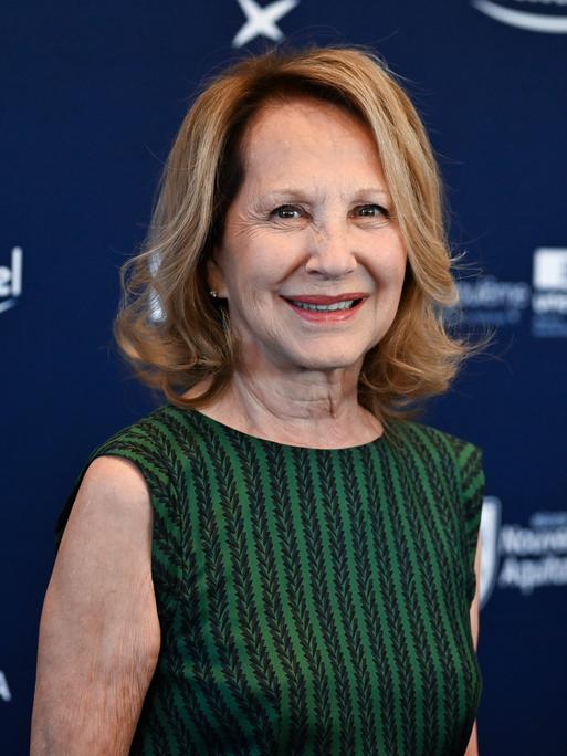 Nathalie Baye bei einem Filmfestival in Angouleme 2024; sie trägt ein grün-gestreiftes ärmelloses Top und lächelt in die Kamera.