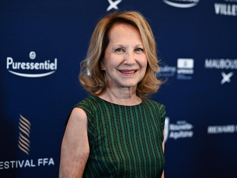 Nathalie Baye bei einem Filmfestival in Angouleme 2024; sie trägt ein grün-gestreiftes ärmelloses Top und lächelt in die Kamera.
