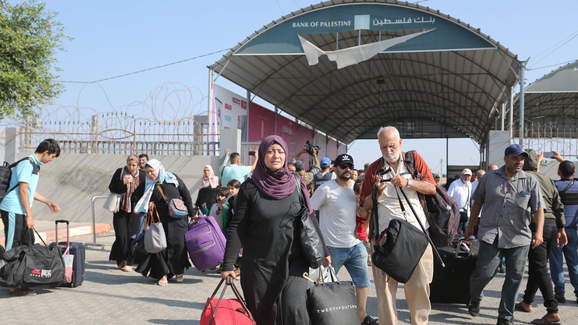 Menschen mit Koffern und Taschen stehen vor dem Grenzübergang Rafah.,