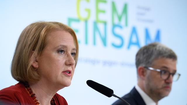 Lisa Paus (l, Bündnis 90/Die Grünen), Bundesministerin für Familie, Senioren, Frauen und Jugend sitzt auf einem Podium, hinter ihr ist an der Wand eine Präsentation zu erkennen. Sie gibt eine Pressekonferenz im Bundesfamilienministerium, um das Einsamkeitsbarometer mit Zahlen zum Einsamkeitsgefühl in Deutschland vorzustellen.