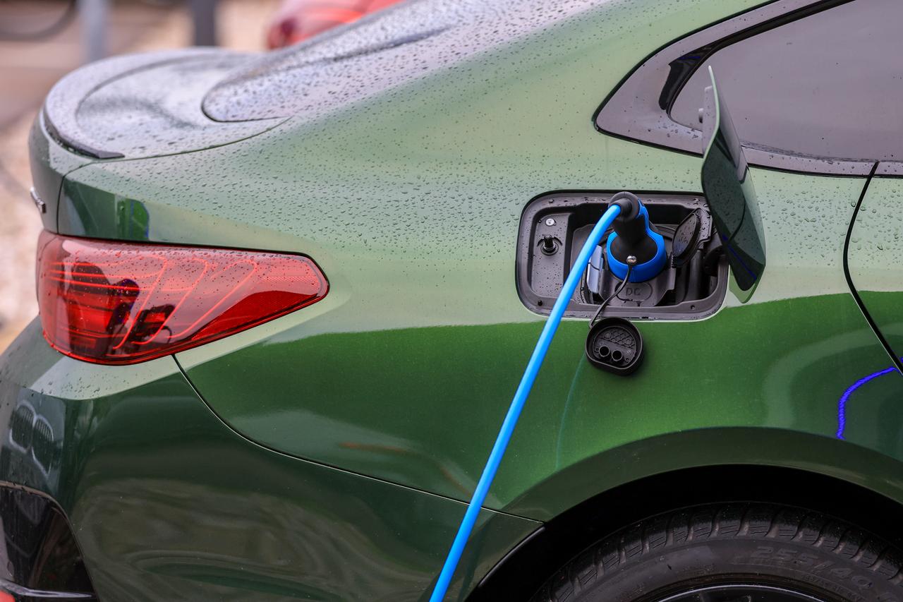 Ein grünes Elektrofahrzeug lädt an einer Ladesäule.