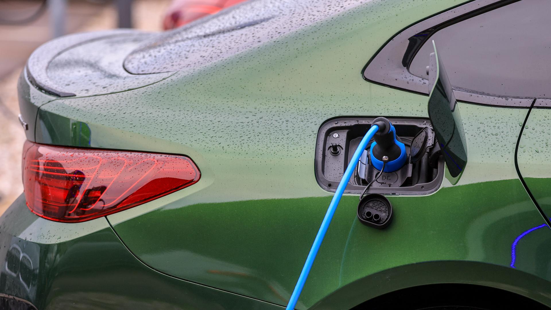 Ein grünes Elektrofahrzeug lädt an einer Ladesäule.