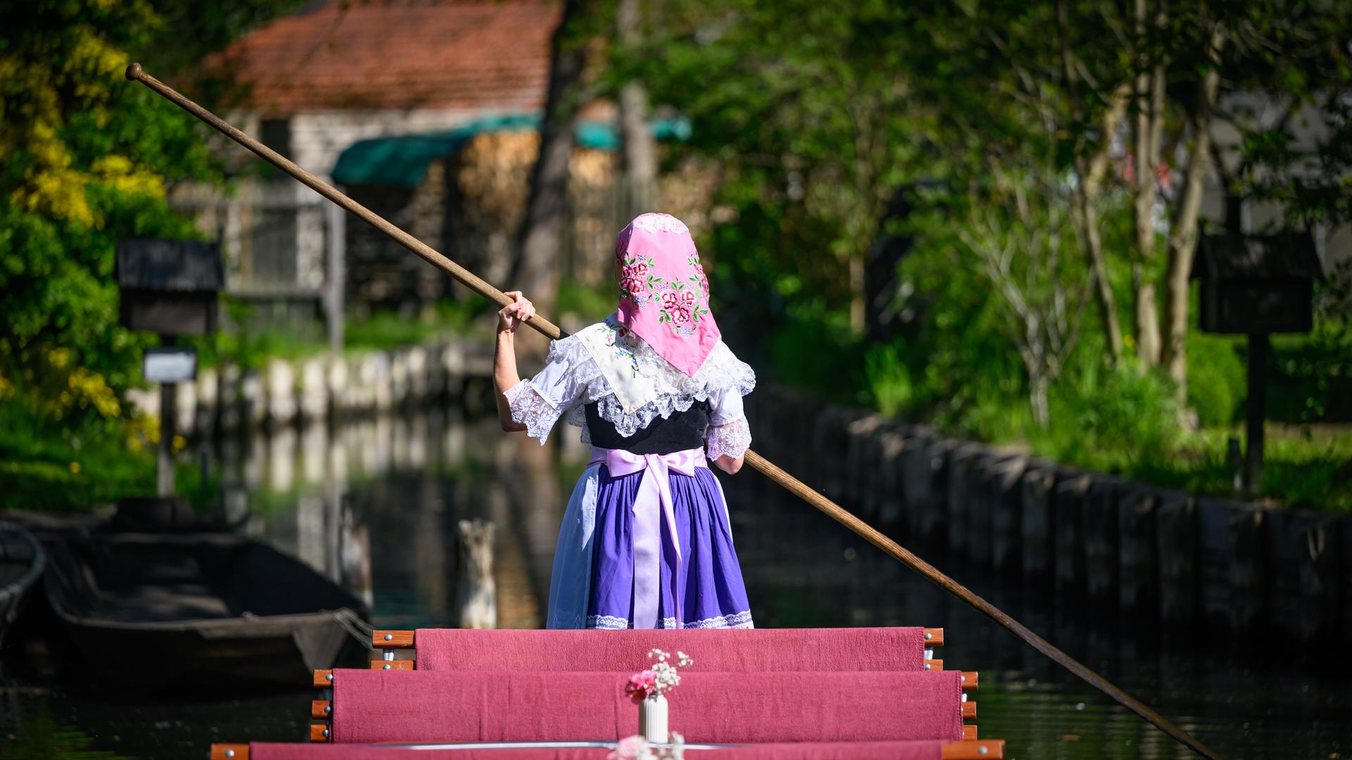 Eine Kahnfährfrau trägt sorbisch-wendische Festtagstracht mit aufwändigen Stickereien und wartet am Rande eines Pressetermins im Spreewald auf einem noch leeren Kahn auf Fahrgäste.