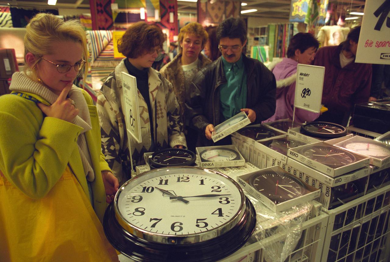 Menschen stehen in einem Ikea-Einrichtungshaus vor lauter Küchenuhren. 