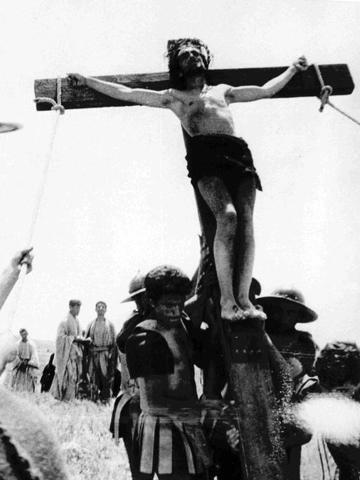 Kreuzzug mit Jesus am Kreuz - ein Schwarz-Weiß-Filmstill aus Pier Paolo Pasolinis Film "Das 1. Evangelium - Matthäus"