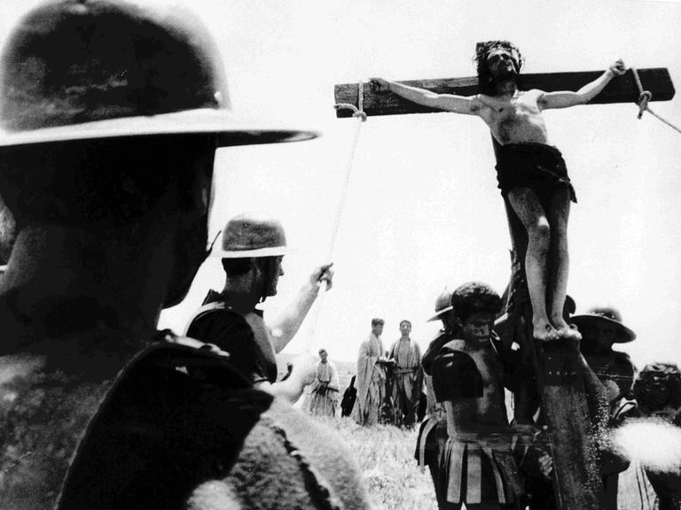 Kreuzzug mit Jesus am Kreuz - ein Schwarz-Weiß-Filmstill aus Pier Paolo Pasolinis Film "Das 1. Evangelium - Matthäus"