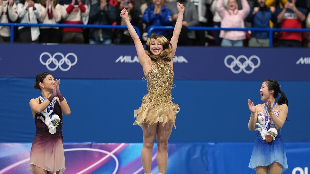 Drei Eiskunstläuferinnen auf dem Podium.