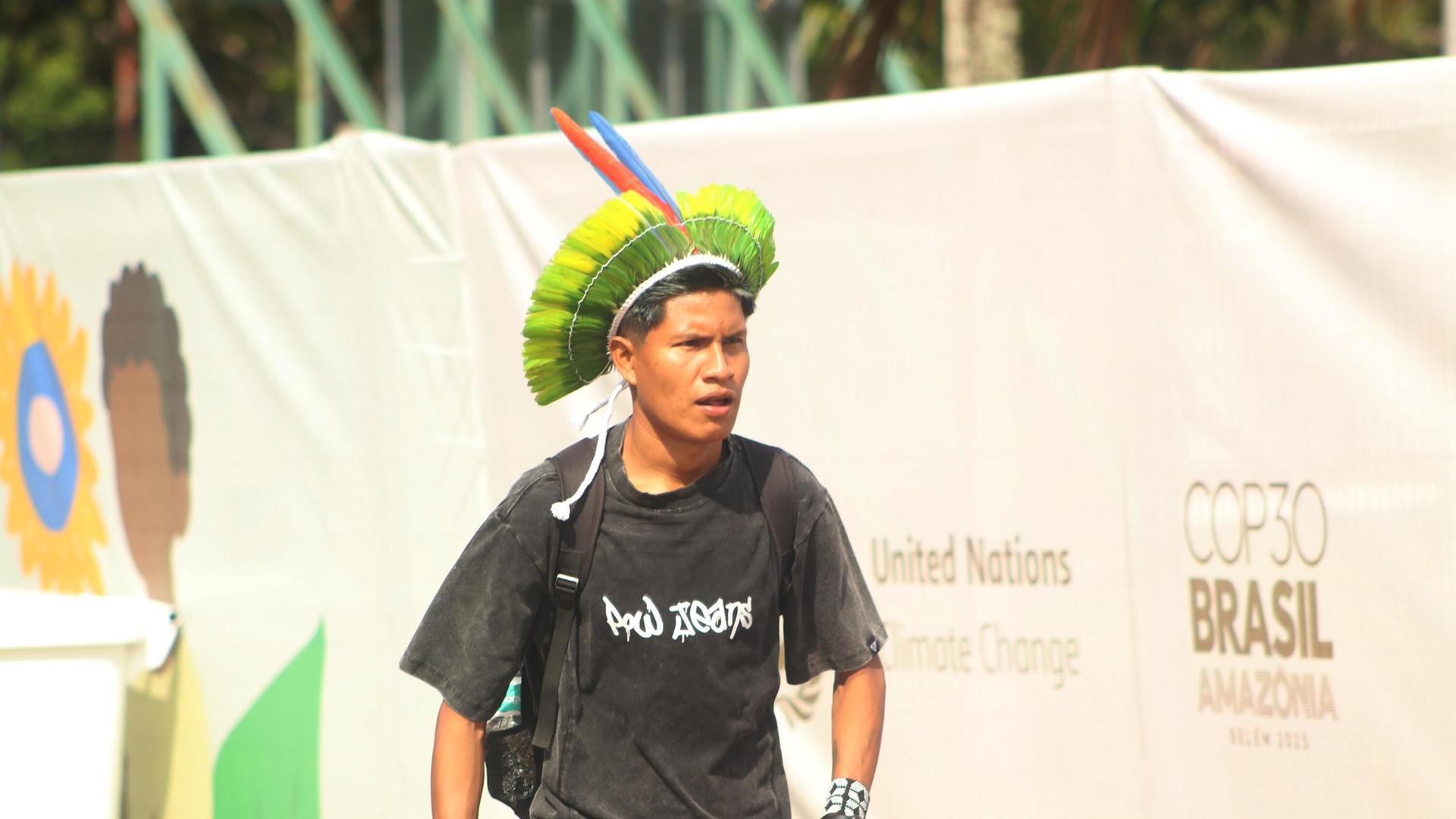 Eine indigene Person geht mit einem traditionellen Kopfschmuck an dem Logo der COP30 in Belém, Brasilien, vorbei Eine indigene Person geht mit einem traditionellen Kopfschmuck an dem Logo der COP30 in Belém, Brasilien, vorbei