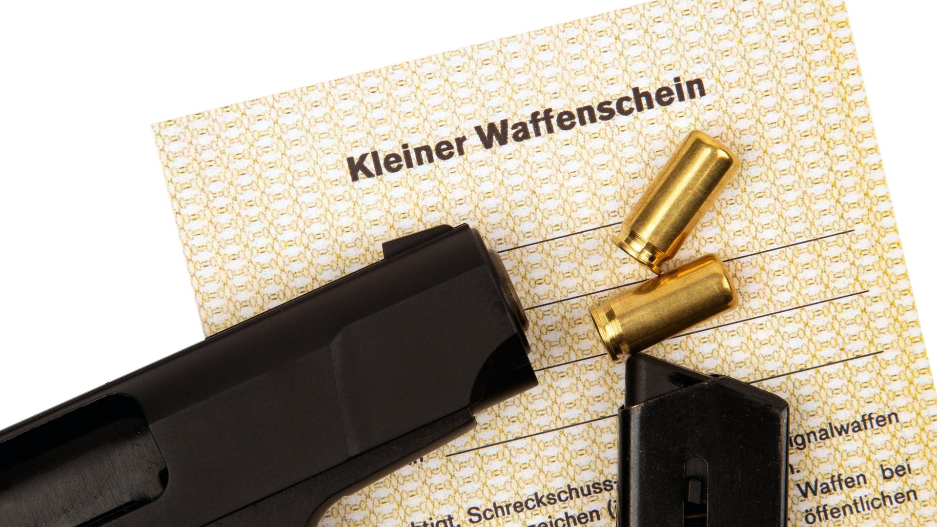 Auf einem Kleinen Waffenschein liegt eine Pistole und Munition.