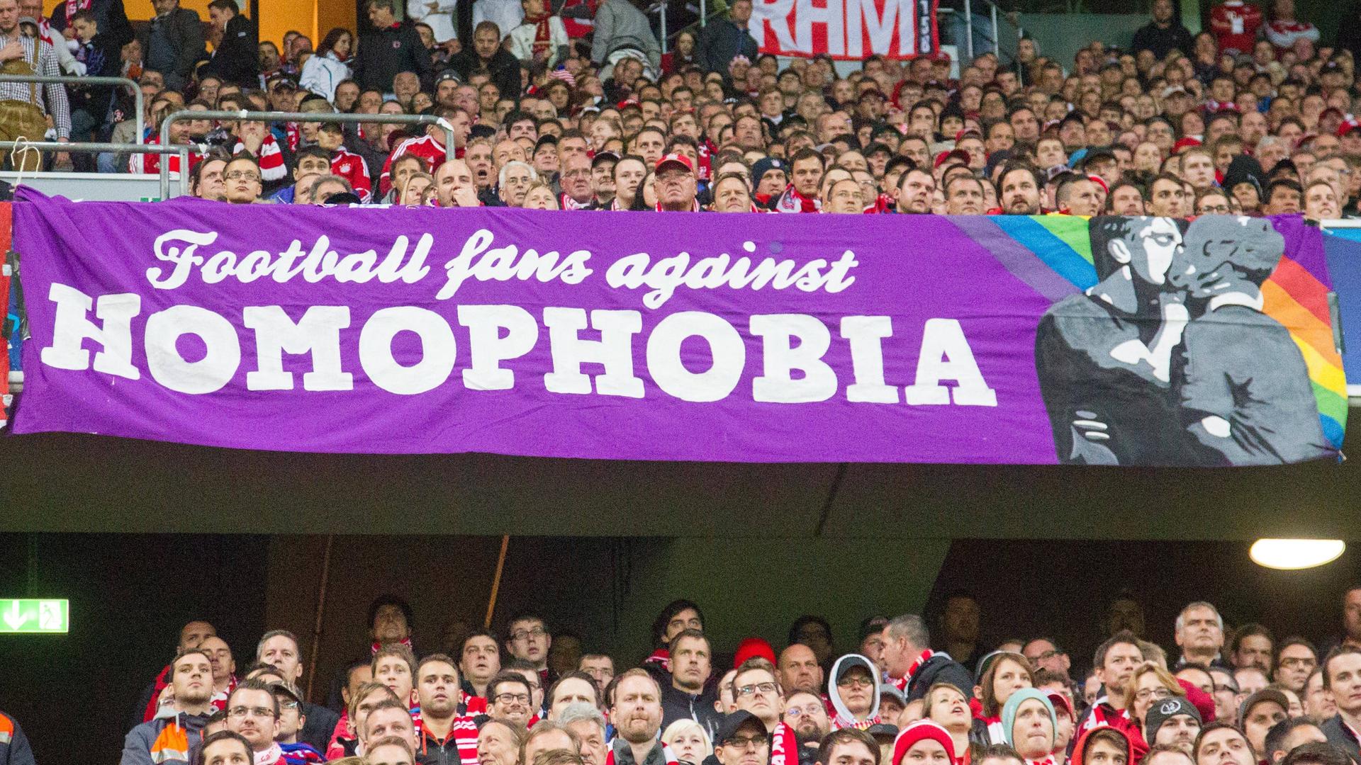 Das Bild zeigt einen Ausschnitt von Fans in einem Stadion, sie halten ein Banner hoch, auf dem zu lesen ist: Football fans against Homophobia.